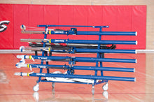 Blue, equipment carrier with volleyball uprights, nets, and pads on it in a gym.