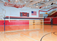 Indoor sports facility with a Spalding Elite Aluminum volleyball system and American flag on wall.