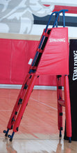 Volleyball freestanding referee platform with a red, 6 piece protective pad system in a gym.