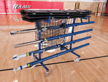 Blue volleyball equipment cart in a gym with volleyball systems, padding, and nets on it.